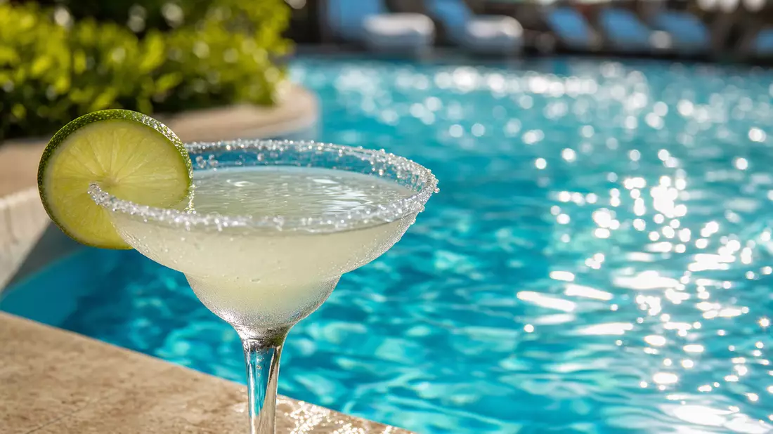 Makroaufnahme von türkisblauem Poolwasser mit Lichtreflexionen und Cocktailgarnitur