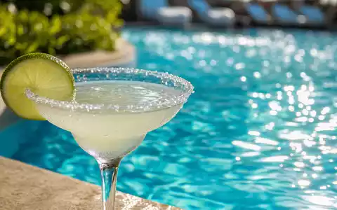 Meliá Hotels International S.A. Makroaufnahme: Nahaufnahme von türkisblauem Poolwasser und Cocktail-Utensilien, ISIN ES0176252718 - Foto: THN