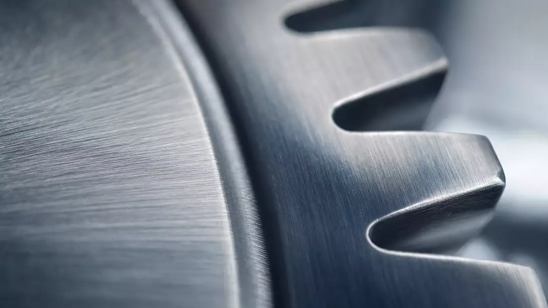 Extreme Makroaufnahme eines gebürsteten Metallzahnrads mit scharfen Zahnkanten