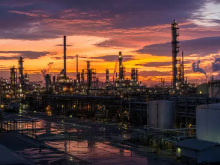 Valero Energy Corp US91913Y1001 zeigt eine Raffinerieanlage bei Dämmerung mit beleuchteten Türmen und Tanks - Foto: THN