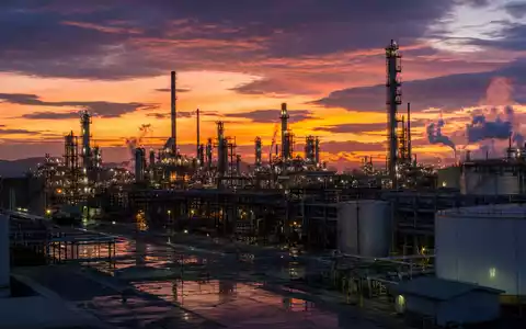 Valero Energy Corp US91913Y1001 zeigt eine Raffinerieanlage bei DĂ€mmerung mit beleuchteten TĂŒrmen und Tanks - Foto: THN