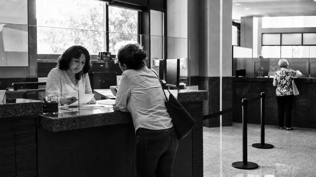 Schwarzweiß-Reportagefoto einer Kundenberatung am Bankschalter