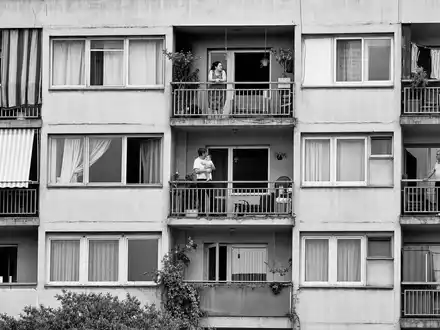 Equity Residential US29476E1073 dokumentarische Schwarzweißfotografie einer städtischen Wohnanlage mit Bewohnern auf Balkonen im Abendlicht - Foto: THN