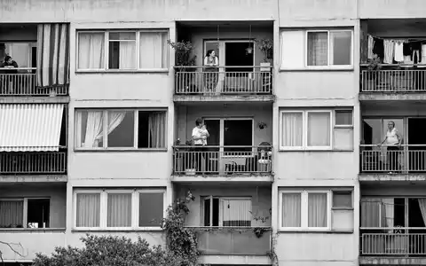 Equity Residential US29476E1073 dokumentarische Schwarzweißfotografie einer städtischen Wohnanlage mit Bewohnern auf Balkonen im Abendlicht - Foto: THN