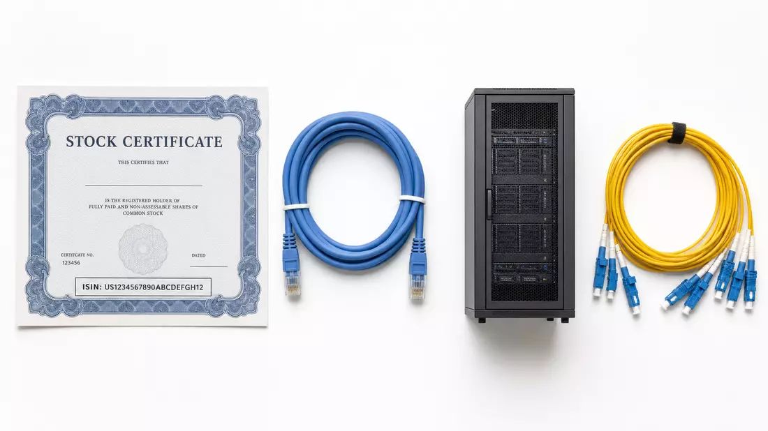 Flatlay-Arrangement mit Aktienzertifikat, Patchkabeln und Serverrack-Miniatur auf weißem Untergrund