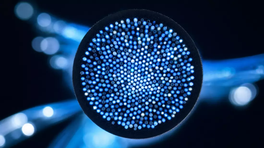 Makro Foto Glasfaserkabel Querschnitt mit leuchtenden blauen Lichtpunkten