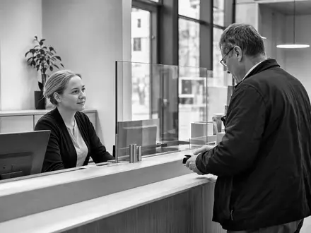 Svenska Handelsbanken (SE0007100599) setzt auf persönliche Beratung am Schalter, dokumentiert in dieser Schwarzweiß-Reportageaufnahme einer Filiale - Foto: THN
