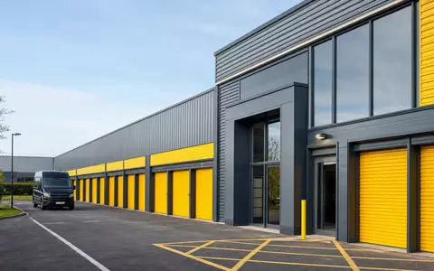 Big Yellow Group plc (ISIN GB0002869419): fotorealistische Außenansicht einer modernen Selfstorage-Anlage mit gelben Rolltoren - Foto: THN