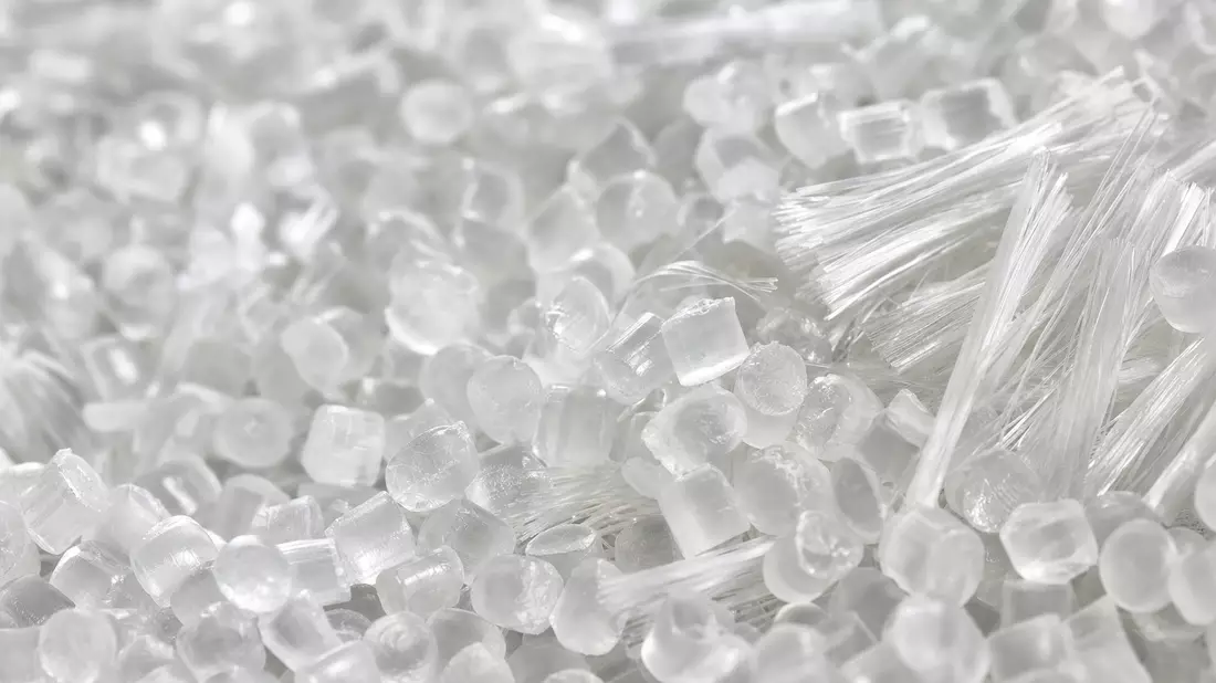 Makroaufnahme von transparenten Polymergranulaten und feinen Fasern