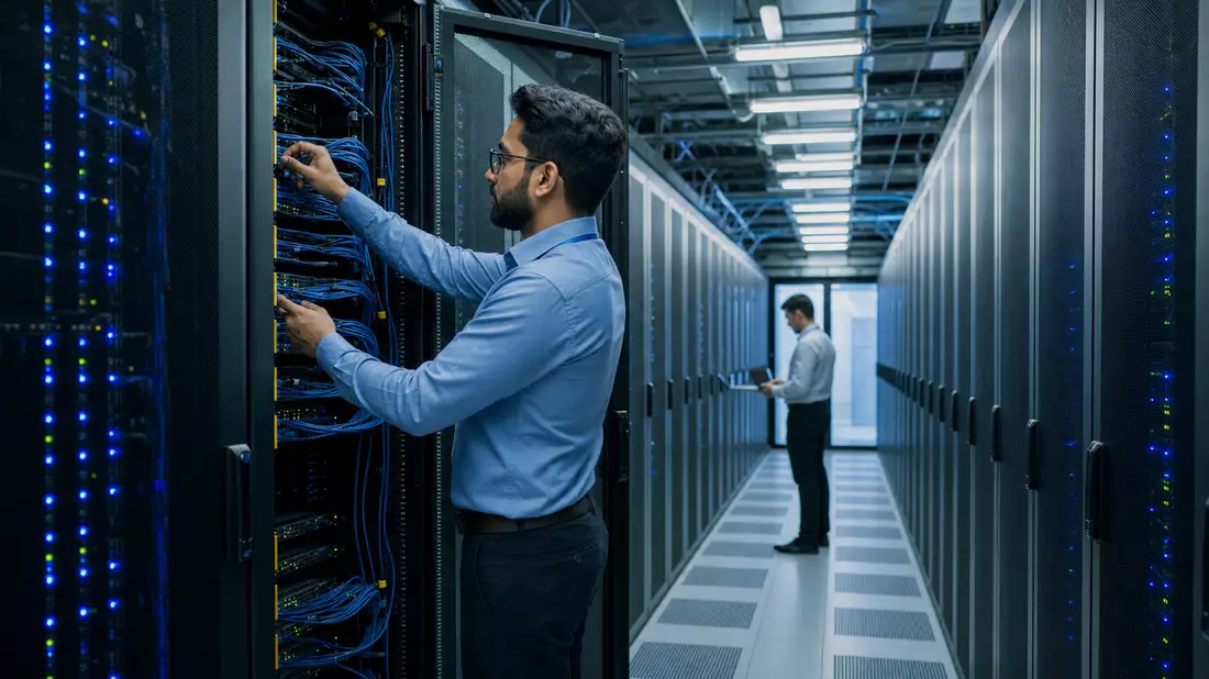 Techniker warten Serverschränke in modernem Rechenzentrum mit blauer LED-Beleuchtung
