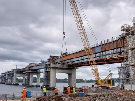 Balfour Beatty plc (ISIN GB0002422382) zeigt fotorealistisch eine Brückenbaustelle mit Kran und Arbeitern am Wasser - Foto: THN