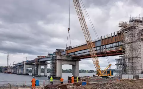 Balfour Beatty plc (ISIN GB0002422382) zeigt fotorealistisch eine Brückenbaustelle mit Kran und Arbeitern am Wasser - Foto: THN