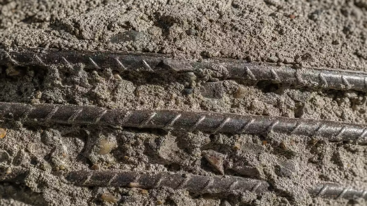 Makroaufnahme von texturiertem Beton mit sichtbaren Stahlbewehrungsstäben
