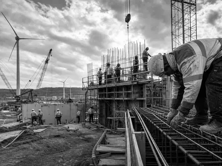 Dokumentarisches Schwarzweiß-Reportagefoto zeigt Baustelle und Windkraftanlagen, verbunden mit Acciona S.A., ISIN ES0125220311, weltweitem Infrastrukturprojekt - Foto: THN