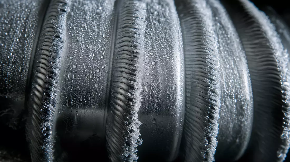 Extreme Nahaufnahme einer gewellten Metall-Membranstruktur mit Frost