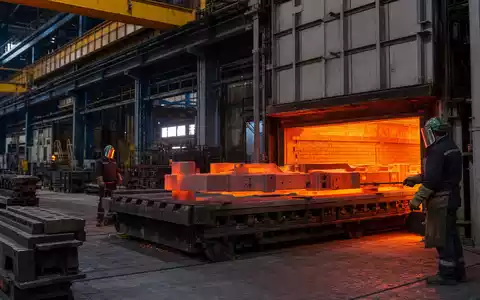 Fotorealistische Aufnahme einer Wärmebehandlungsanlage von Bodycote plc, ISIN GB00B3FLWH99, mit glühenden Stahlteilen im Industrieofen - Foto: THN