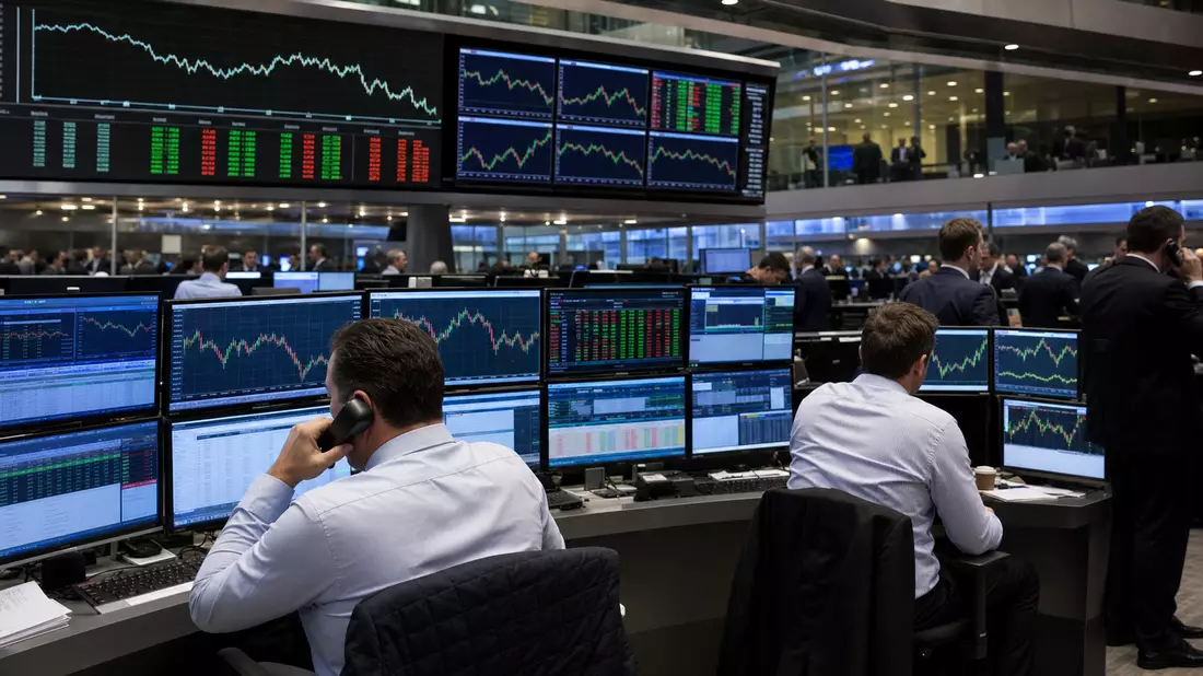 Trader an Bildschirmen mit Finanzcharts auf einem Handelsboden