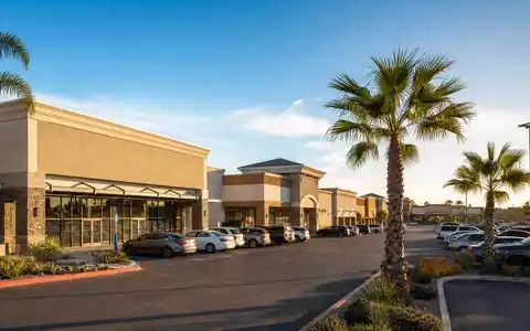 Fotorealistisches Bild eines Einkaufszentrums passend zu Kimco Realty, ISIN US49446R1095, sonniger Nachmittag mit Parkplatz - Foto: THN