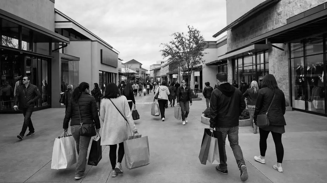 Schwarzweißfoto von Menschen mit Einkaufstüten in einer Ladenpassage