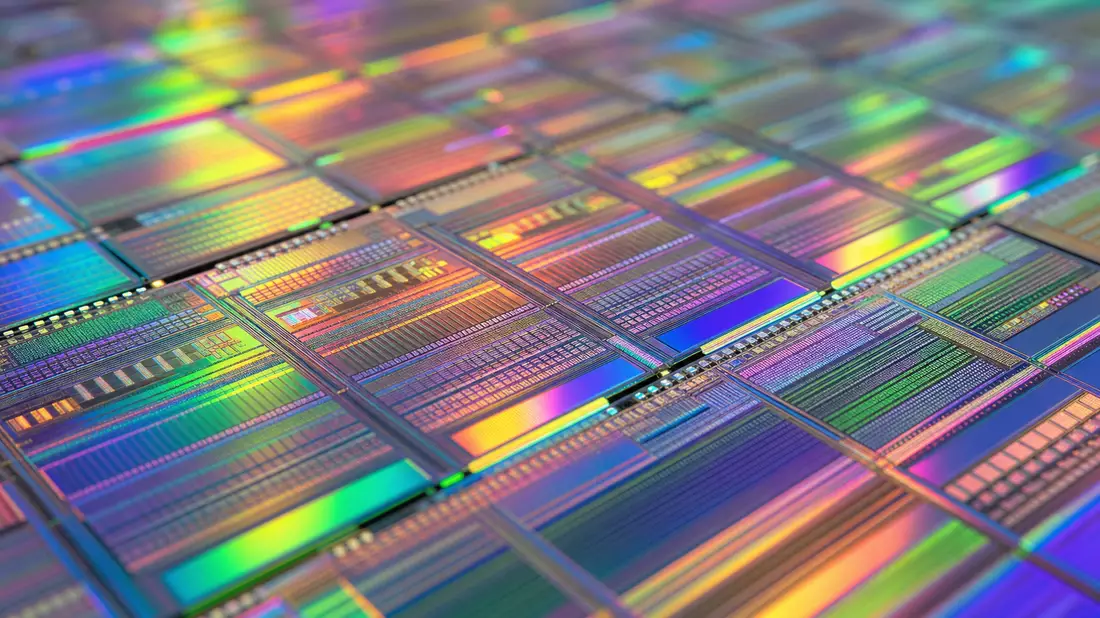 Extreme Nahaufnahme eines Siliziumwafers mit schillernden Schaltkreismustern in Regenbogenfarben