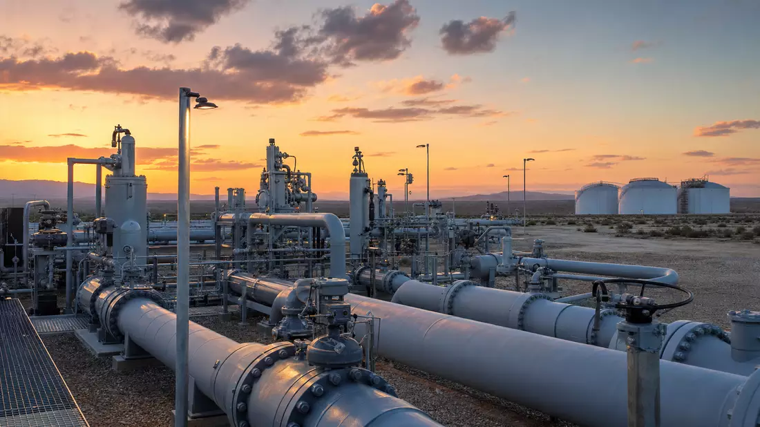 Erdgas-Pipeline-Anlage im Abendlicht mit Tanks und Ventilen in weiter Landschaft