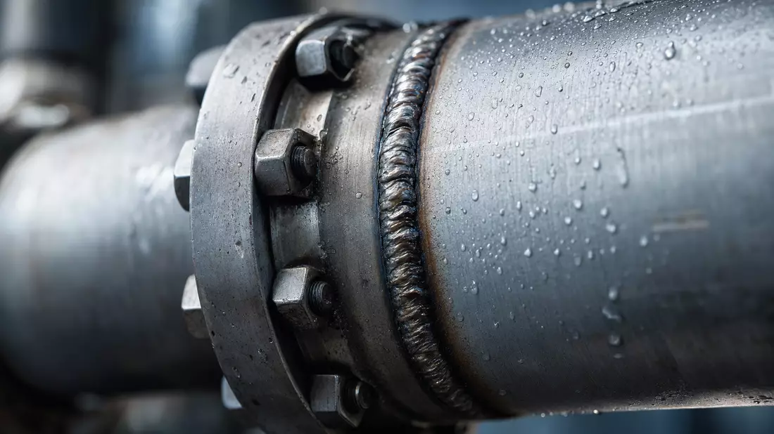 Extreme Nahaufnahme einer Pipeline-Schweißnaht mit Wassertropfen auf Metall