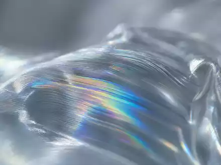 Amcor plc JE00BJ1F6598 extreme macro of iridescent rainbow interference patterns on transparent polymer film surface - Foto: THN