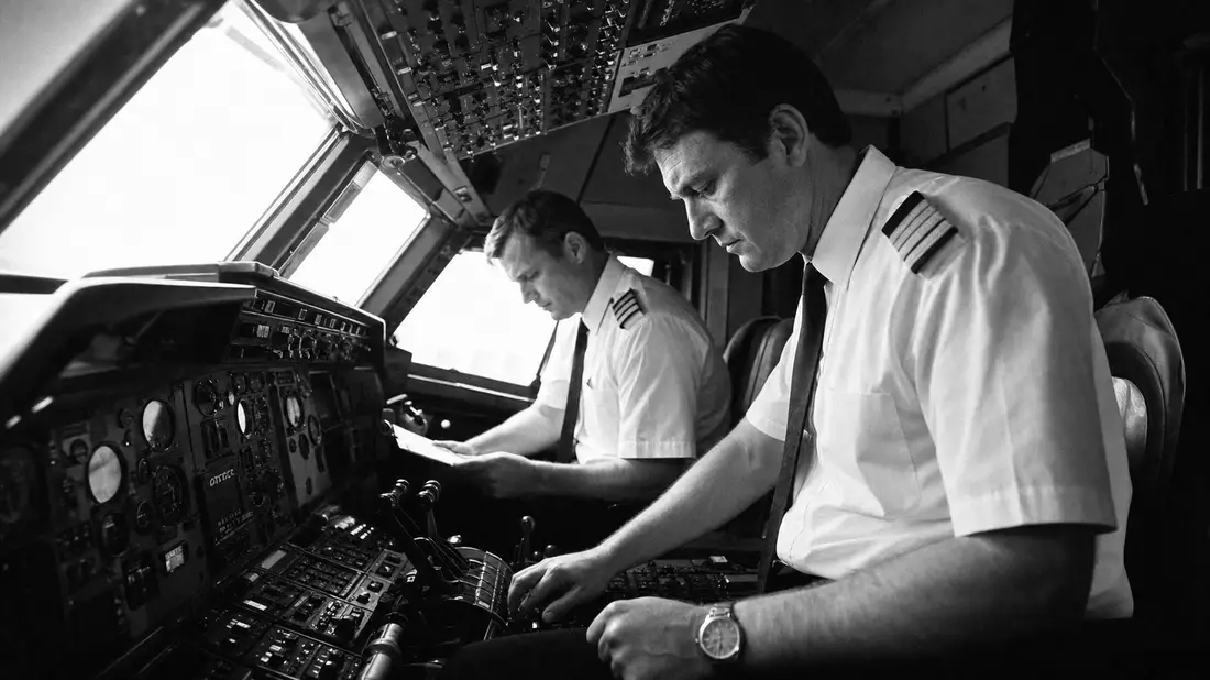 Zwei Airline-Piloten in Uniform bei Pre-Flight-Checks im Cockpit, Schwarz-Weiß-Reportagefoto, Instrumentenblock, American Airlines Group US02376R1023