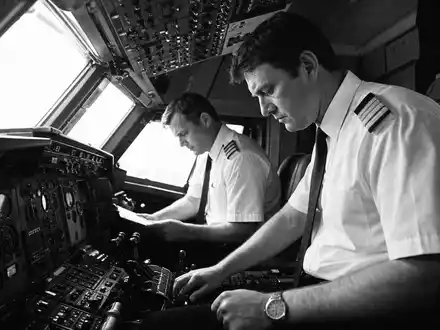 American Airlines Group Aktie US02376R1023 Schwarz-Weiß-Reportage zwei Piloten Cockpit-Vorflugkontrolle an komplexem Instrumentenpanel - Foto: THN