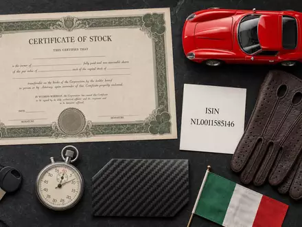 Ferrari N.V. NL0011585146: Flatlay mit Aktienzertifikat, ISIN-Karte, rotem Sportwagen-Modell sowie Stoppuhr und Fahrhandschuhen - Foto: THN