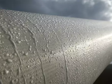 Makroaufnahme einer Rotorblattoberfläche mit Regentropfen zeigt Materialdetail typisch für Ørsted A/S, ISIN DK0060094928, Offshore-Windkraftanlagen - Foto: THN