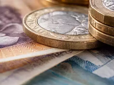 Lloyds Banking Group (GB0008706128) verwaltet Einlagen in britischer Währung, symbolisiert durch Pfund-Banknoten und Münzen - Foto: THN
