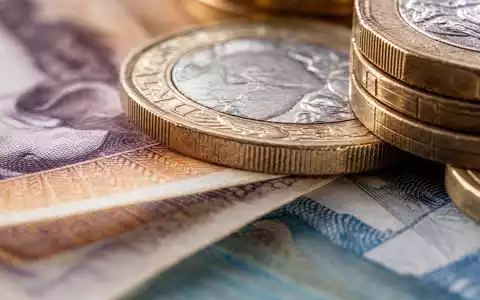 Lloyds Banking Group (GB0008706128) verwaltet Einlagen in britischer Währung, symbolisiert durch Pfund-Banknoten und Münzen - Foto: THN