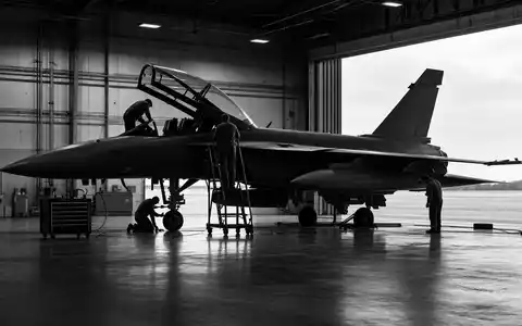 BAE Systems plc (ISIN GB0002634946) wartet Militärjets, dokumentiert in dramatischer, körniger Schwarzweiß-Reportage-Fotografie einer Werkshalle - Foto: THN