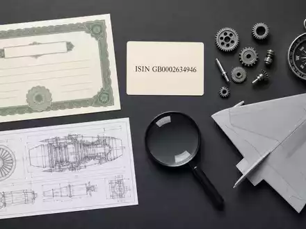 BAE Systems plc (ISIN GB0002634946) symbolisiert durch Aktienzertifikat, ISIN-Karte und Technikutensilien im Flatlay - Foto: THN