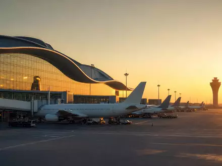 Fotorealistisches Bild zeigt Flughafen-Terminal bei Sonnenuntergang, passend zu Aena S.M.E. S.A., ISIN ES0105046009, Luftfahrtinfrastruktur - Foto: THN