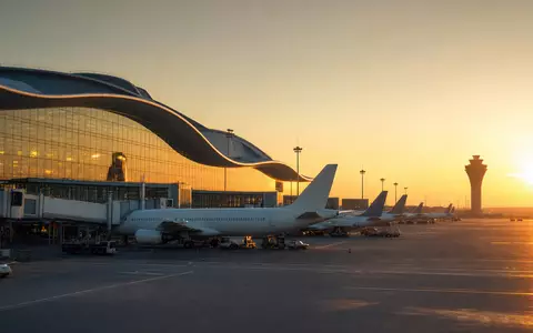 Fotorealistisches Bild zeigt Flughafen-Terminal bei Sonnenuntergang, passend zu Aena S.M.E. S.A., ISIN ES0105046009, Luftfahrtinfrastruktur - Foto: THN
