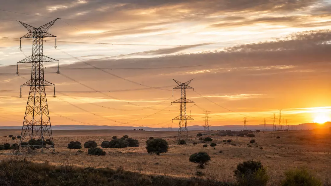 Hochspannungsmasten bei Sonnenuntergang, Symbolbild für Redeia Red Eléctrica