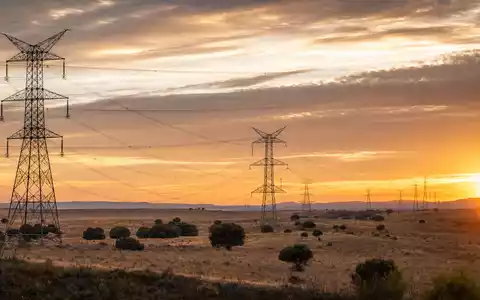 Fotorealistische Hochspannungsmasten in Kastilien symbolisieren Redeia (Red Eléctrica), ISIN ES0173093024, Stromnetzbetreiber bei Sonnenuntergang - Foto: THN