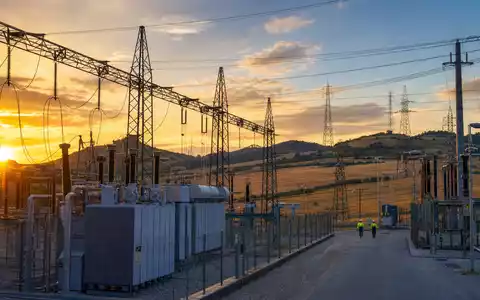 Terna - Rete Elettrica Nazionale IT0003242622 zeigt Hochspannungs-Umspannwerk mit Strommasten in Hügellandschaft bei Sonnenuntergang - Foto: THN