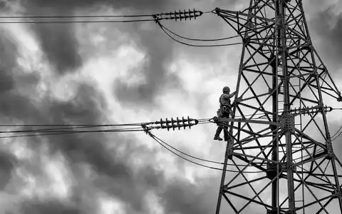 Terna - Rete Elettrica Nazionale IT0003242622 schwarzweiße Reportage zeigt Techniker beim Klettern auf hohem Strommast - Foto: THN