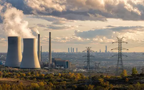 Endesa S.A. ES0130670112 zeigt Kraftwerk mit Kühltürmen und Hochspannungsmasten vor Madrider Skyline im Abendlicht - Foto: THN