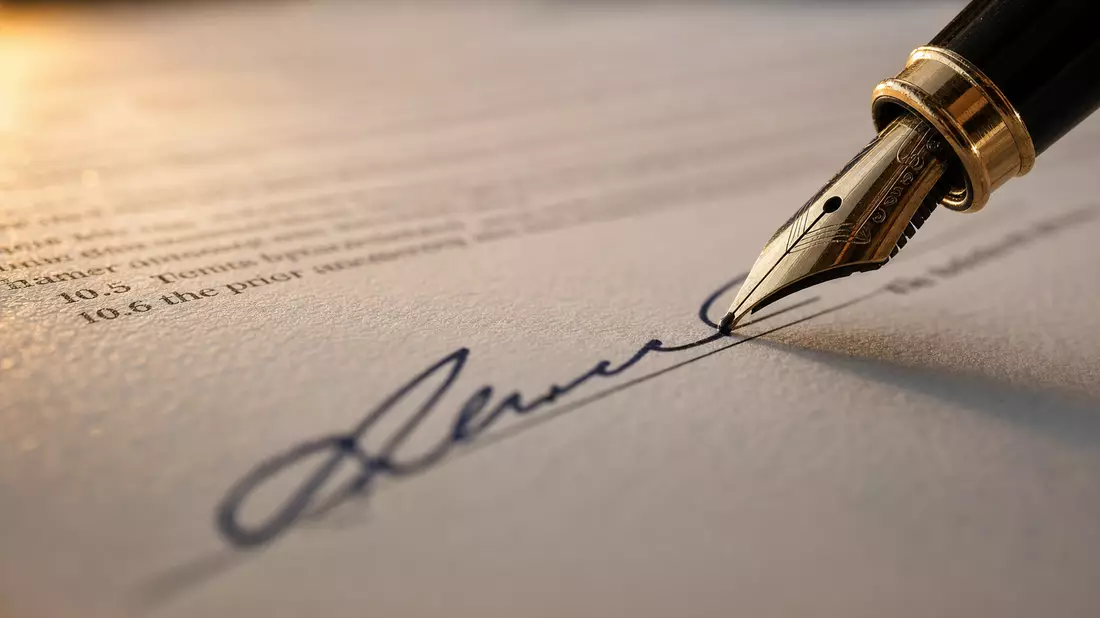Nahaufnahme eines Füllfederhalters bei der Unterschrift auf Vertragsdokument