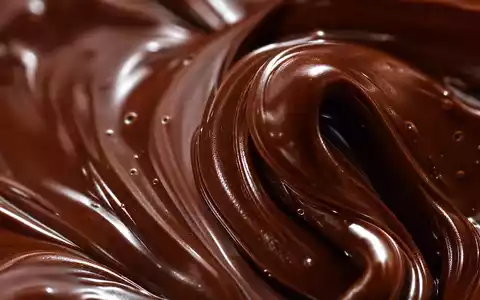 Chocoladefabriken Lindt & Sprüngli AG (CH0010570759) zeigt Makroaufnahme von wirbelnder geschmolzener dunkler Schokolade in Nahaufnahme - Foto: THN