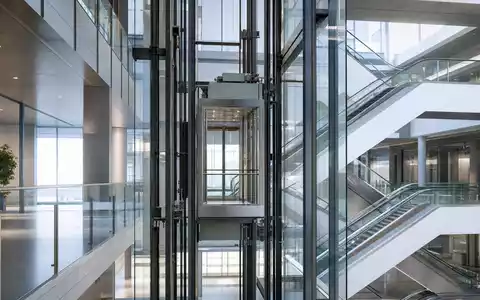 Schindler Holding AG (ISIN CH0024638196) zeigt gläsernen Aufzugschacht mit Rolltreppen in modernem Bürogebäude-Atrium - Foto: THN