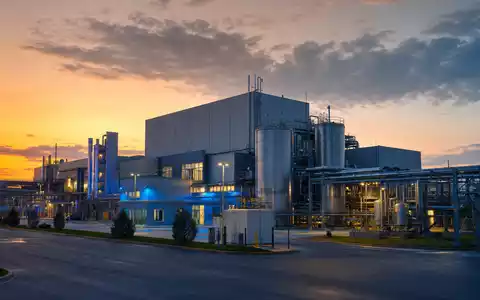 Fotorealistische Pharma-Produktionsanlage bei Dämmerung symbolisiert Pfizer Inc. mit ISIN US7170811035 im Biotech-Sektor - Foto: THN