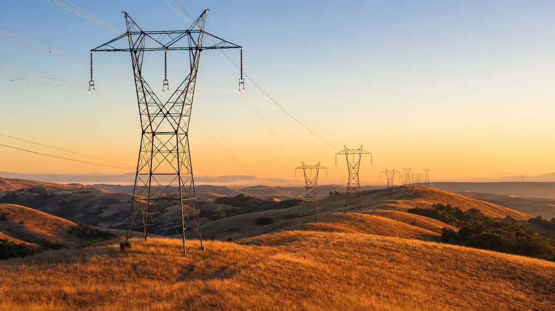Hochspannungsmasten in goldenen kalifornischen Hügeln bei Sonnenuntergang