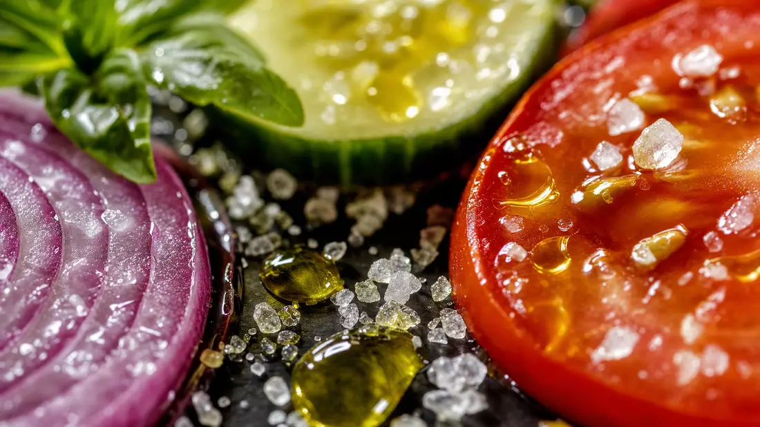 Makroaufnahme von Gemüsescheiben mit Olivenöltropfen und Salzkristallen