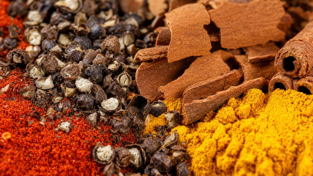 Makroaufnahme von Pfeffer, Paprika, Kurkuma und Zimt in leuchtenden Farben
