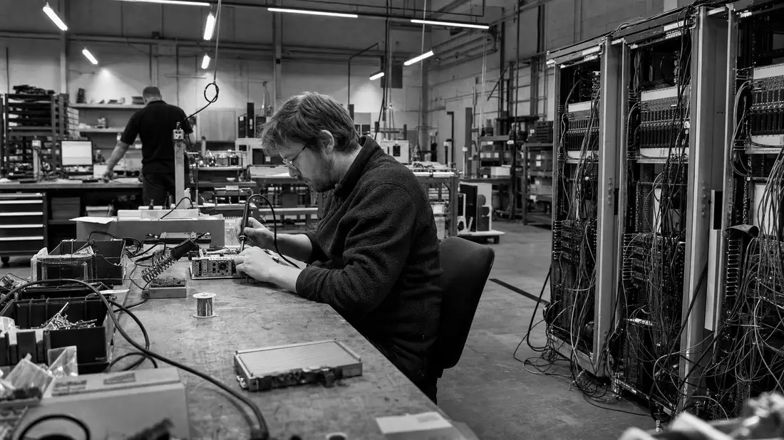 Schwarzweiß-Reportagefoto eines Ingenieurs beim Löten in Elektronikwerkstatt